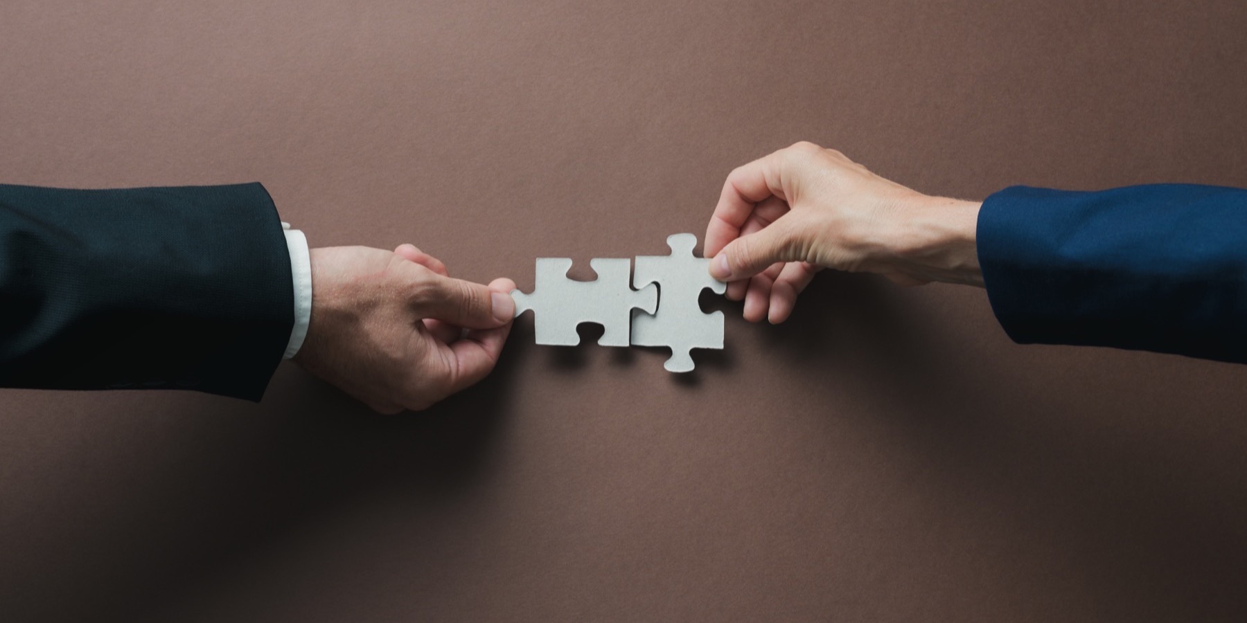 Two hands joining puzzle pieces, representing crypto wallets connecting to merchant checkout